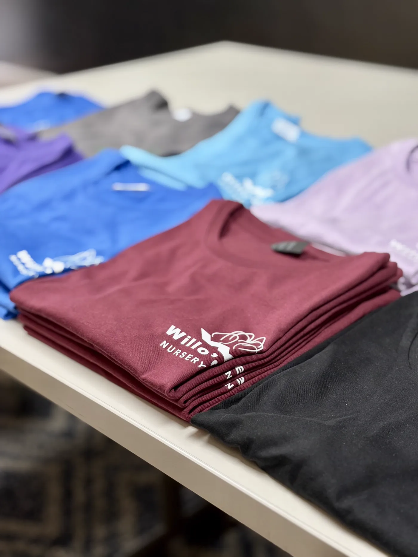 Folded DTF printed shirts for a Willow Nursery apparel order